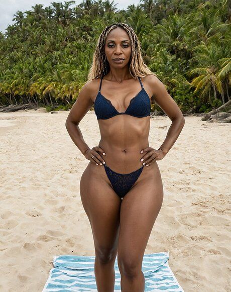 Black model with a fit figure poses on a beach in various stages of undress - #1