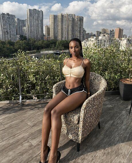 Pretty black girl with her hair braided stands naked on a rooftop patio - #7